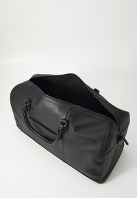 Black leather duffel bag with textured surface, zippered opening, two handles, and an inner pocket for organization.