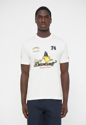 Valkoinen puuvillainen t-paita, jossa on pyöreä kaula-aukko, painettuna grafiikka, jossa on keltainen ankannuppu sekä mustaa ja punaista tekstiä. Normaali istuvuus.