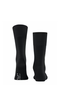 Un paio di calze nere a crew con polsini a coste, una delle quali presenta il testo del marchio sulla suola, esposte in posizione verticale su uno sfondo bianco.