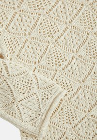 Stickad tröja i krämfärg, med diamantsmönster och öppen vävdetaljer samt ribbad mudd. Mjuk textur och lätt design.