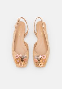 Zapatos de slingback trenzados en color beige con punta cuadrada, adornados con embellishments florales y detalles decorativos en la parte frontal.