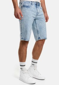 Pantaloni scurți din denim, de culoare bleu deschis, cu croială lejeră, design cu cinci buzunare și tiv franjurat. Asortați cu adidași albi și șosete cu dungi.