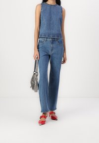 Top sin mangas de denim y jeans de cintura alta en azul claro. Presenta un diseño de corte recto, combinado con zapatos rojos y un bolso plateado.