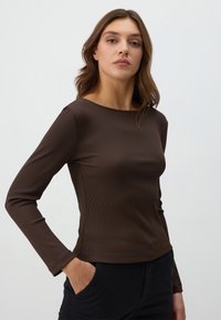 Bruine geribbelde lange mouw top met een ronde halslijn, getailleerd silhouet en een gladde textuur, gecombineerd met zwarte broek.