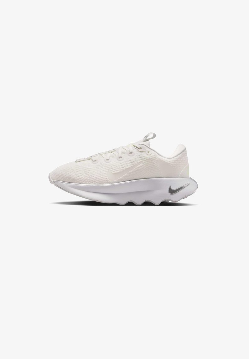 Baskets de sport blanches avec tige en tissu texturé, semelle blanche épaisse et logos Nike argentés sur le côté et la semelle intermédiaire, vues du côté gauche.