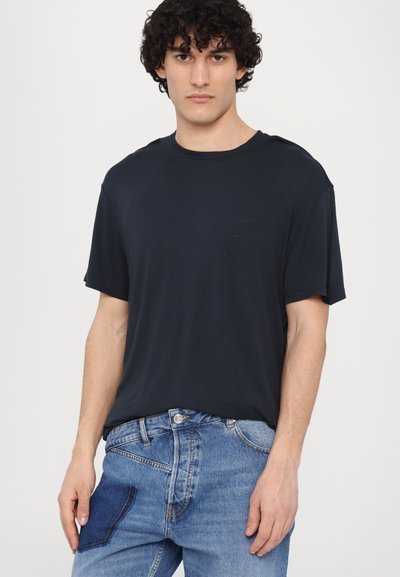 T-shirt à manches courtes bleu marine en matériau doux avec une coupe décontractée et un col rond, associé à un jean en denim bleu clair avec une poche à rabat.