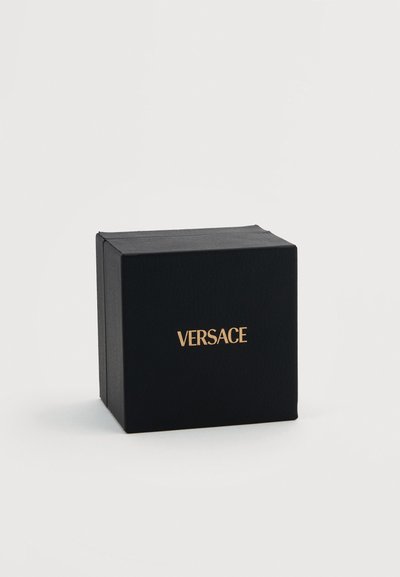 Μαύρο υφασμάτινο κουτί δώρου με χρυσό λογότυπο "VERSACE" τοποθετημένο στο κέντρο της πρόσοψης, σε απλό λευκό φόντο.