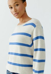 Gestreifter Pullover in Beige und Blau, mit weitem Ausschnitt, lockerer Passform und weicher Textur. Das Design umfasst horizontale Streifen und gerippte Ränder.