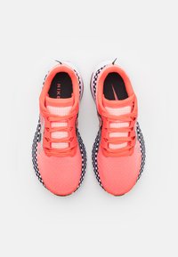 Scarpe da corsa Nike con una vivace tomaia corallo, dettagli a scacchi in bianco e nero, materiale a rete traspirante e lacci piatti.