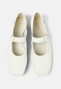 Weiße Leder-Mary-Jane-Schuhe mit rundem Zehenbereich, seitlichem Schnallenverschluss und Ausschnittdesign. Weiche Innenauskleidung sichtbar. Markennamen "Camper" innen gedruckt.