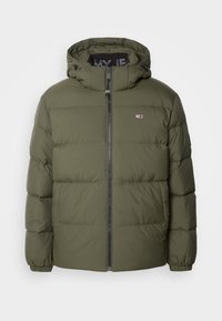 Olivgrön puffjacka med dragkedjestängning, justerbar huva och horisontell sömnad. Har logotypdetalj på bröstet och elastiska ärmslut.