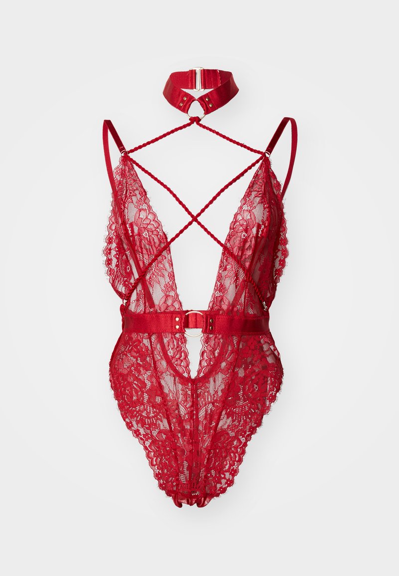 Punainen pitsibody, jossa on syvä V-aukko, ristikkäiset hihnat ja leveä kangashihna, jossa on pyöreä metallikoriste. Mukana tulee sopiva kaulapanta.