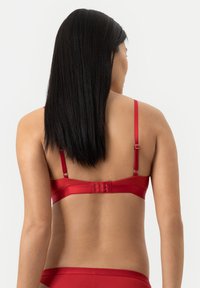 Punainen satiininen rintaliivi säätölenkeillä ja hakaskiinnityksellä takana, jossa on sileä pinta ja minimalistinen muotoilu.