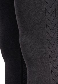 Svarta träningsleggings med en texturerad mönstring och slät finish, med zigzagdetaljer längs sidan för extra design.