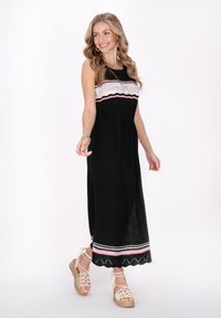 Rochie maxi tricotată neagră, cu detalii multicolore țesute la bust și talie legată. Prezintă un tiv ondulat și o mică fanta pe lateral.