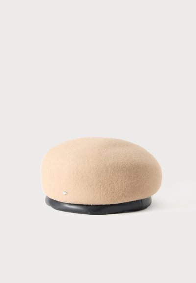 Béret en laine beige avec un bandeau en cuir noir et un petit ornement argenté sur le côté, présenté sur un fond uni clair.