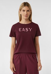 Burgunderfarbendes T-Shirt mit "EASY" Grafik in zartem Rosa, Rundhalsausschnitt, kurzen Ärmeln und weichem Baumwollmaterial, kombiniert mit passenden Hosen.