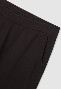 Pantaloni sportivi neri realizzati in tessuto morbido, con vita elastica e tasche laterali. Taglio dritto con dettagli di design minimi.