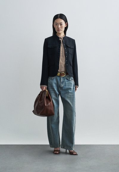 Mørk denimjakke med fire forlommer, stribet skjorte under, lyseblå højtaljede jeans, brun læderhåndtaske og sandaler med hæl.