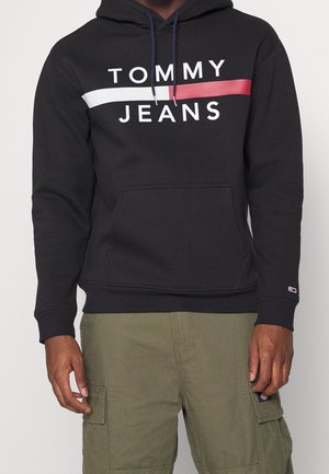 Hoodie noir en mélange de coton avec un graphique à rayures blanches et rouges et le texte "TOMMY JEANS", capuche avec cordon de serrage et poche kangourou à l'avant.