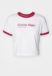 Cropped white t-shirt with red ribbed collar and sleeves. Features glittery red text "Calvin Klein endless city" on the front.