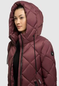 Bordo pūkainais mētelis ar lielu, quilted kapuci; ar melnu rāvējslēdzēju un auklām; gluda, spīdīga tekstūra; diagonāla dimanta raksts.