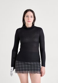 Černý dlouhý rukáv rolák spojený s kostkovanou minisukní. Top má průhlednou texturu a sukně má zvlněný okraj.