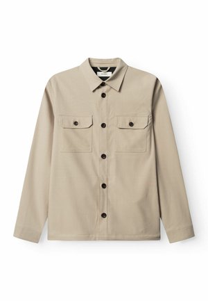 Beiges Hemd zum Knöpfen mit langen Ärmeln, zwei Brusttaschen und dunklen Knöpfen. Glatte Textur, kragenloses Design und minimalistischer Stil.