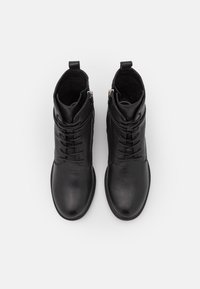 Botas de tobillo de cuero negro con un acabado suave, que cuentan con un cierre de cordones en la parte delantera, dos cremalleras laterales y un diseño de punta redonda.