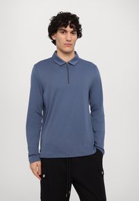 Langærmet blå polo skjorte med lynlås krave, lavet af blødt stof, med en afslappet pasform og minimalistisk design.