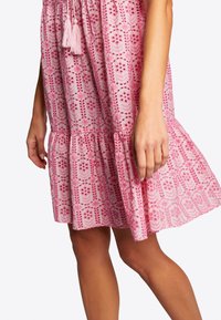 Vestido rosa bordado con patrones florales, dobladillo en capas y acentos de borlas. Tejido liviano con un diseño de corte relajado.