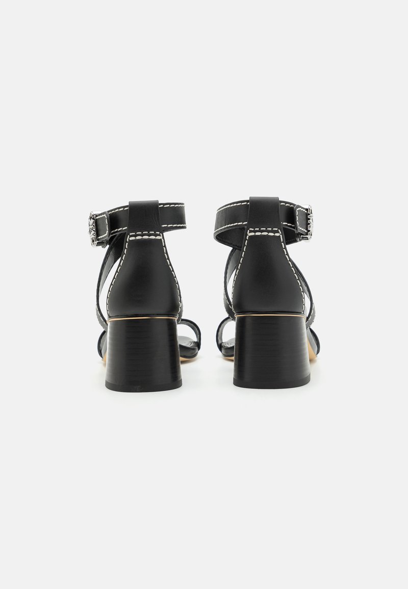 Czarne skórzane sandały na obcasie z blokowym obcasem, paskiem na kostkę z klamrą oraz kontrastowymi białymi szwami.