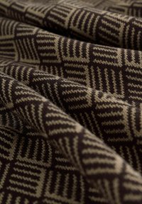 Strukturierter Stoff mit geometrischem Muster in Braun- und Beigetönen, der eine warme und weiche Strickstruktur zeigt.