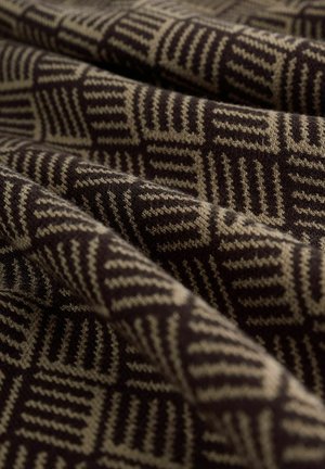 Tissu texturé avec un motif géométrique dans des tons bruns et beiges, mettant en avant une structure de tricot chaude et douce.