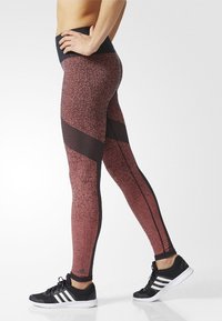 Leggings de patrón rojo y negro con una alta cintura y acentos de malla en los laterales, que presentan un diseño ajustado y una textura suave.