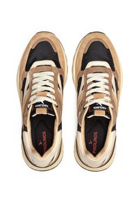 Zapatillas en tonos marrón y negro, con materiales de malla y ante, cordones crema y una suela beige. Presentan una etiqueta de la marca en la lengüeta.