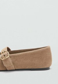 Suede ballet flats vaaleanbeigeissä, jossa on pyöristetyt varpaat, koristeena hihna ja kultainen solki. Tasapohja mukavuutta varten.