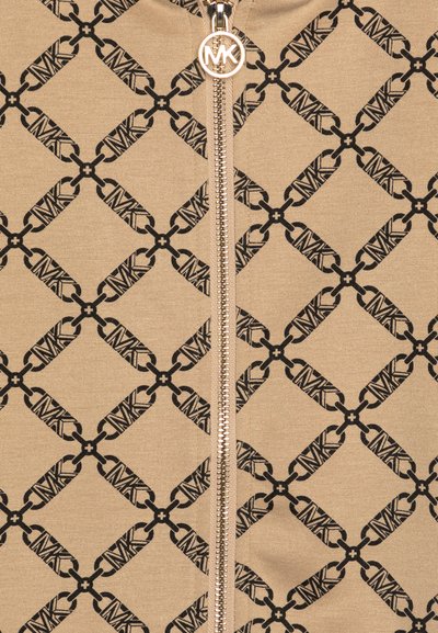 Beige zip-up jacket featuring a patterned design with black logos. The front has a metallic zipper and a smooth, stretchy texture.