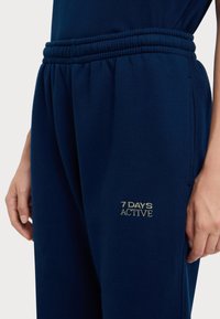 Marineblauwe joggingbroek met een elastische tailleband, met "7 DAYS ACTIVE" geborduurd in het goud. Zachte stof met een comfortabele pasvorm en zijzakken.