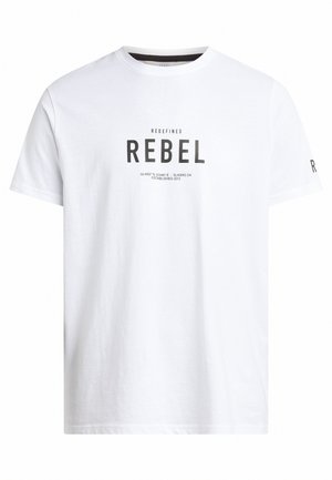 Camiseta de algodón blanca con cuello redondo, mangas cortas y texto impreso "REDEFINED REBEL" en negro. El texto incluye coordenadas y año.