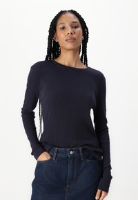 Mørkeblå ribbet langermet topp med rund hals, brukt med høy midje denimskjørt, med en avslappet passform og teksturert overflate.