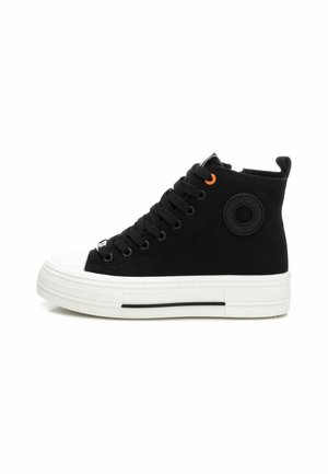 Zapatillas altas negras de lona con suela de goma. Entre sus características se incluyen la puntera blanca, cordones negros gruesos y un acento naranja en el ojal.