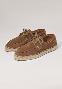 Chaussures en daim marron avec un design à lacets, comportant une semelle de style espadrille et une bordure en jute tissé. Bout rond et détails matériels minimaux.