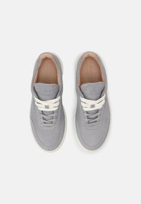 Sneaker in pelle grigia con una finitura liscia, dotate di lacci bianchi, perforazioni minime e una suola di colore chiaro a contrasto.
