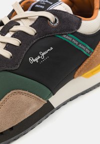 Baskets en tissu noir, avec des accents verts, des détails en suède marron et des lacets beige. Dotées d'une semelle intermédiaire blanche et du logo "Pepe Jeans London".