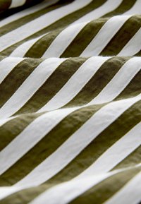 Bavlněná látka s diagonálními pruhy v olivově zelené a bílé barvě, s jemnou strukturou a měkkým, hladkým povrchem.