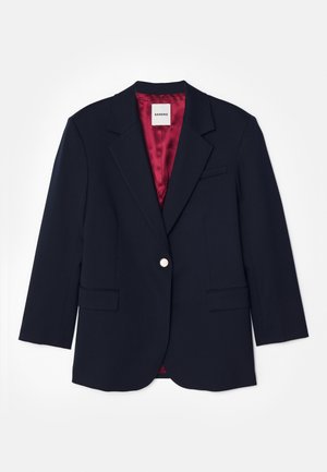 Marineblazer med en tætsiddende design, enkelt sølvknaplukning, to frontlommer og rød satinforing. Blød tekstur, skræddersyet form.