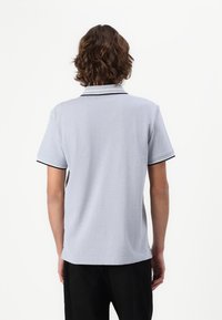 Lys grå polo t-shirt med korte ærmer, der har en kontrasterende sort krave og ærmekant, tekstureret stof og en klassisk pasform.