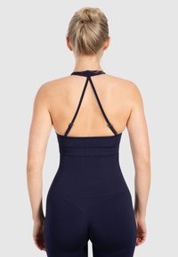 Top deportivo ajustado de color azul marino con tirantes ajustables, textura acanalada y diseño tipo racerback, que destaca una silueta ceñida y suave.