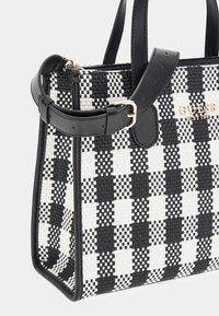 Sac fourre-tout tissé en noir et blanc à carreaux, avec des accents en cuir synthétique, présentant une forme structurée et un détail en logo doré sur le devant.